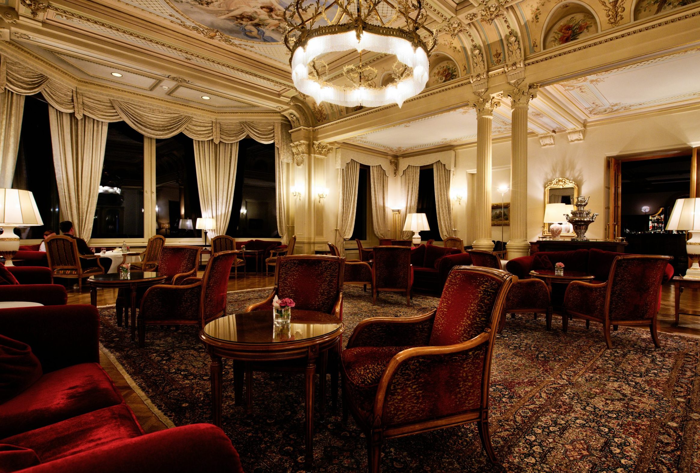 opulent hotel lounge with red velvet chairs, chandeliers, and elegant decor for œlysium wine experiences